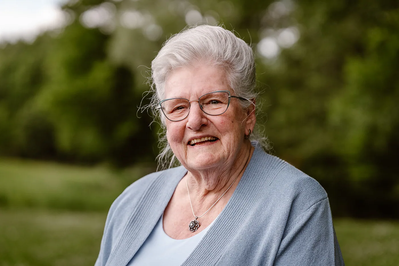 Portret van de oudste vrouw van de familie, lachend, het park onscherp achter haar