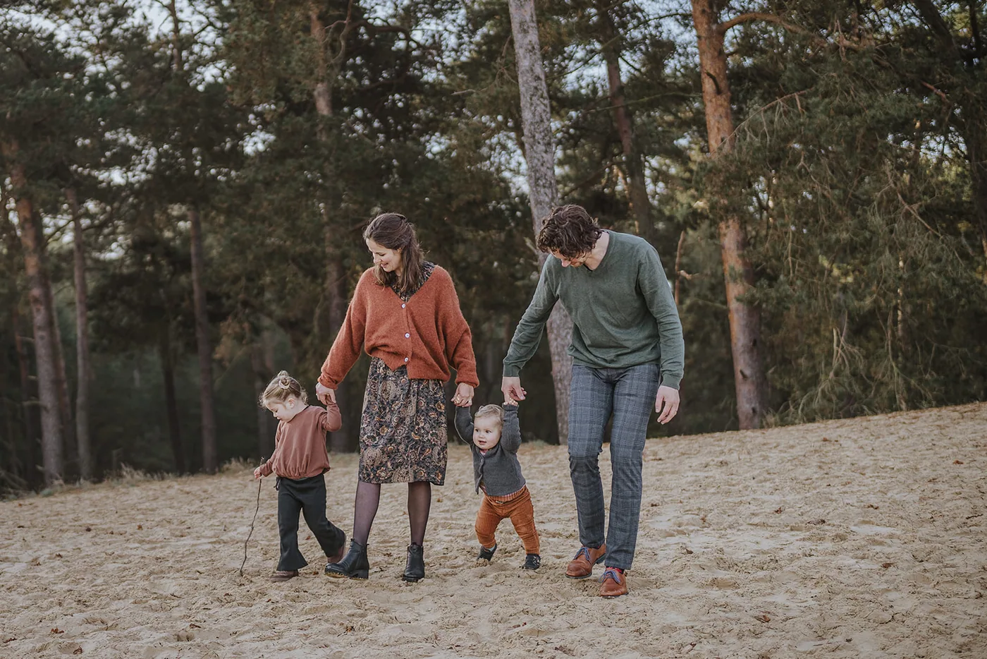 Gezin loopt met twee kleine kinderen door het duinzand