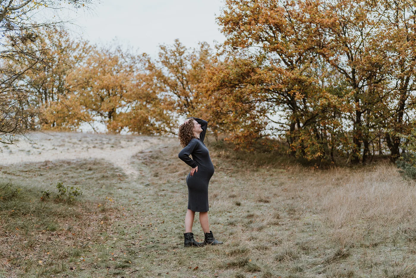 Zwangere vrouw staat stil in een herfstig duinlandschap