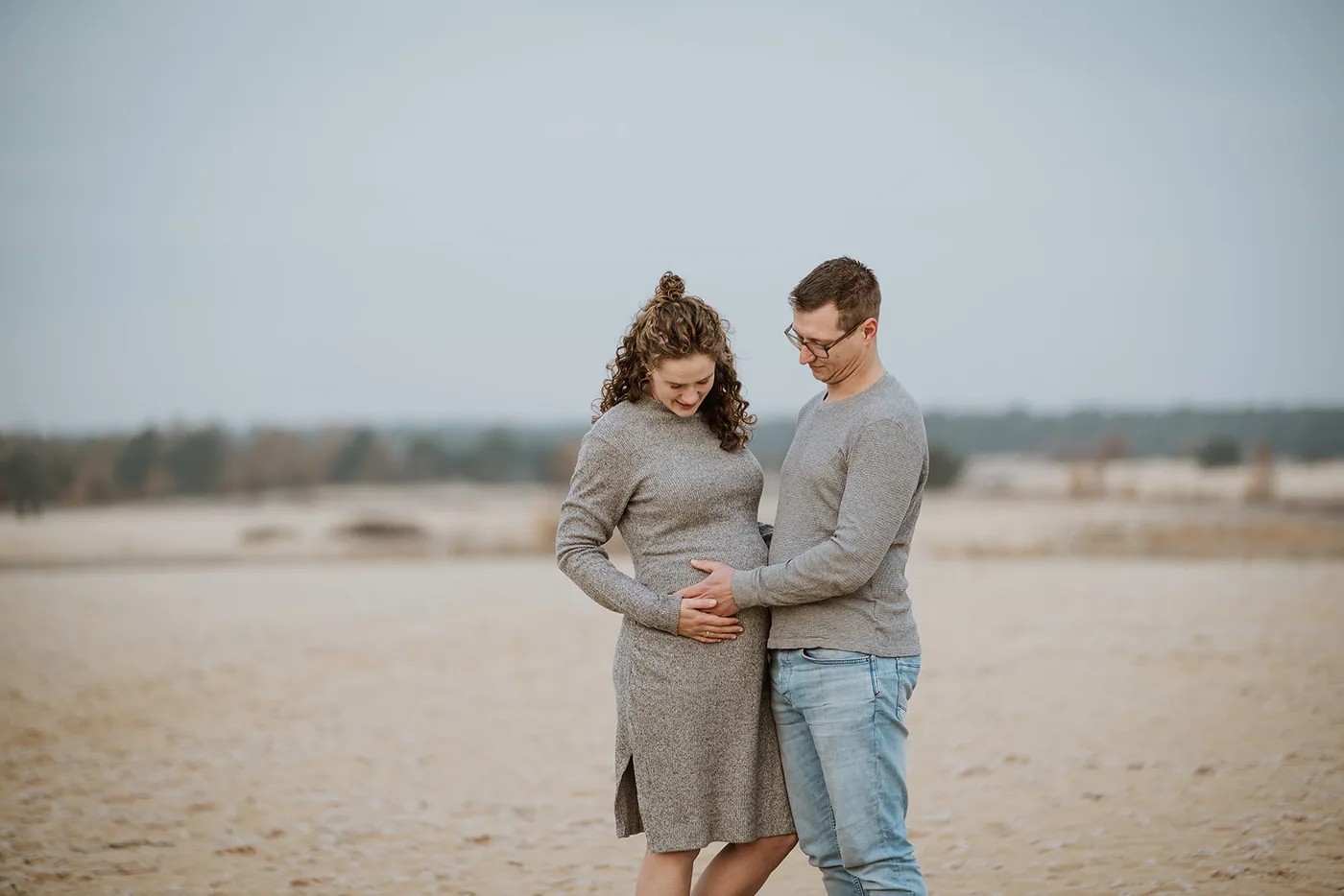 Aanstaande ouders kijken samen naar de buik, ver in het open duin