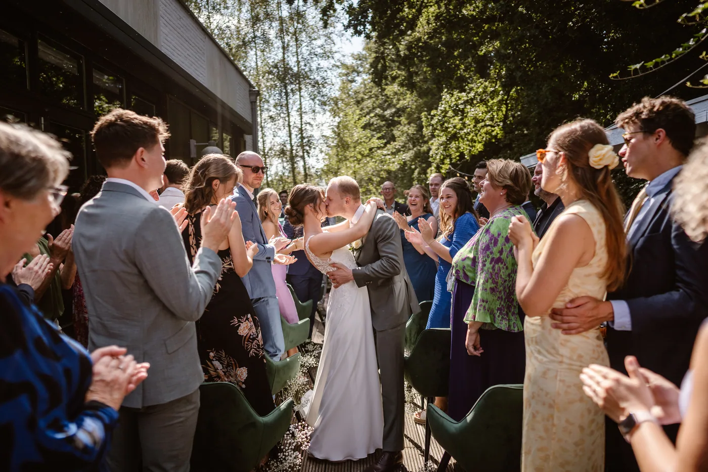 Bruidspaar omhelst elkaar tussen twee rijen applaudisserende gasten